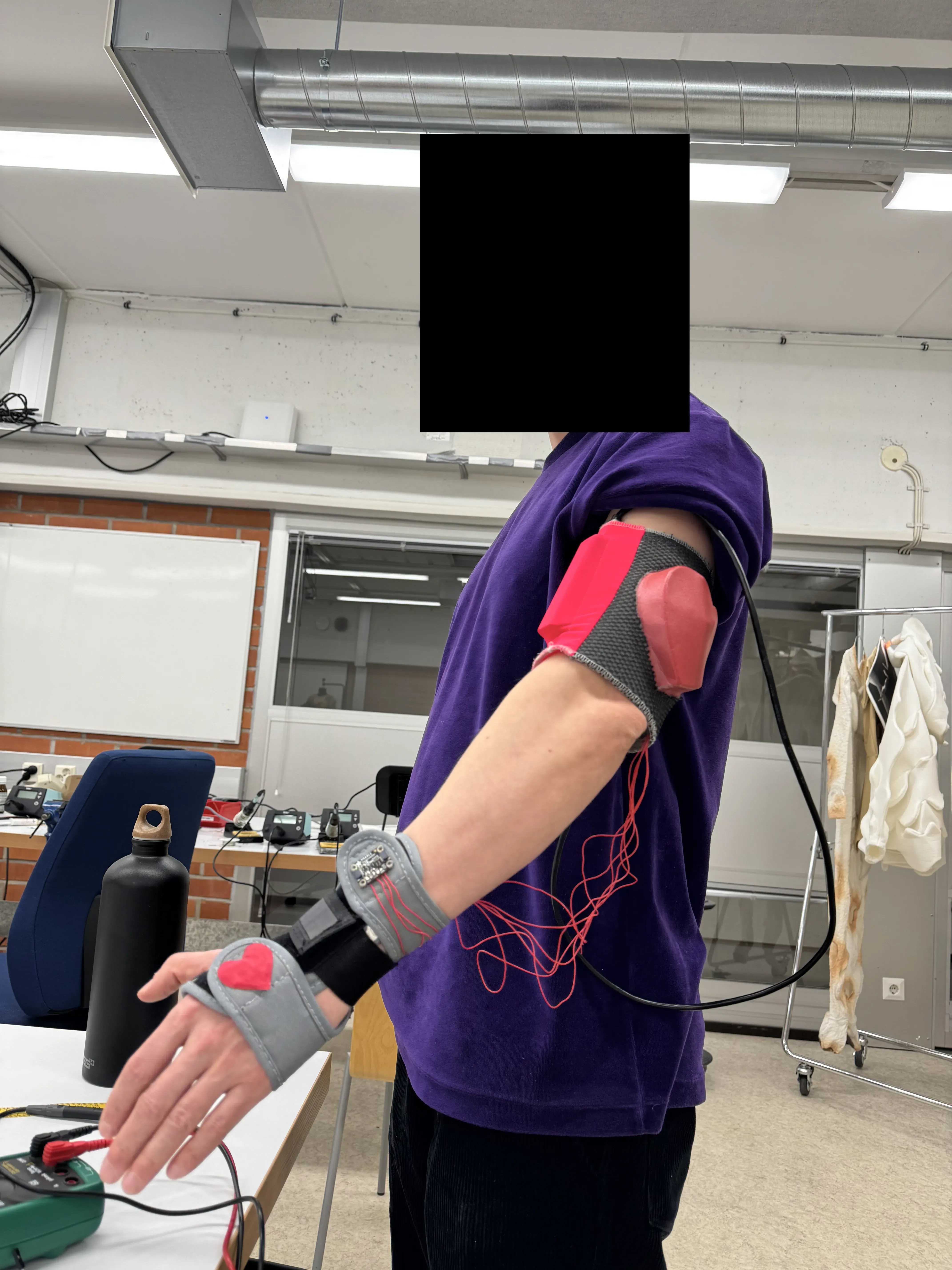 Portrait picture of a man wearing a glove with attached electronic components. His face is censored for privacy purposes.