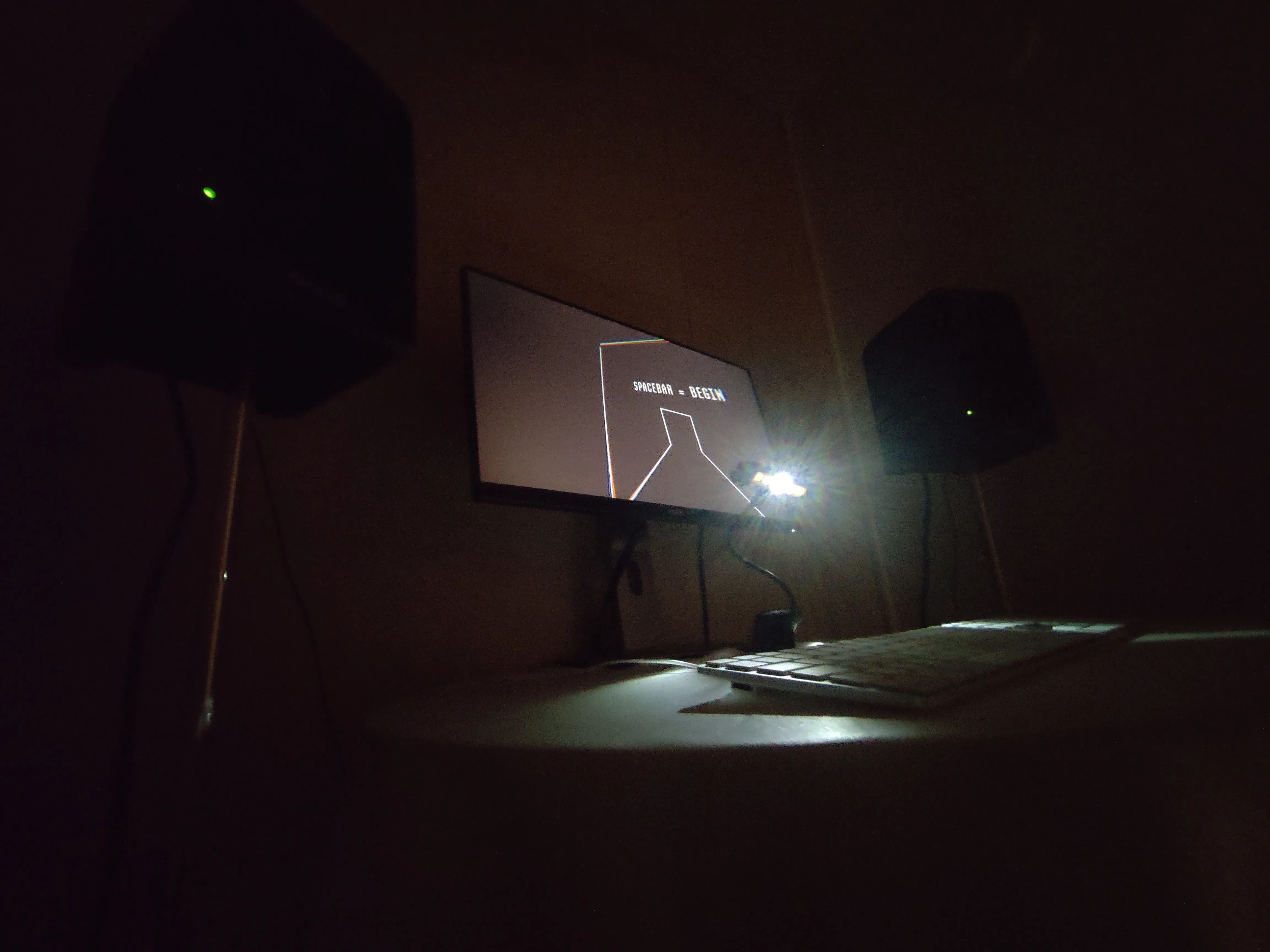 Monitor and speakers in a dark room, displaying Latecomers! by Bruno Norrå